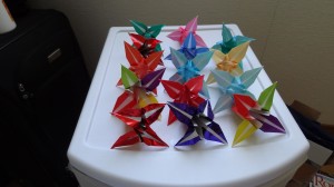 14 origami lilies of different colors and shades on a white table