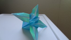 A single light blue sparkly origami lily on a white countertop