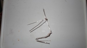 A few pieces of wire bent to resemble a line drawing of a person sitting on their feet