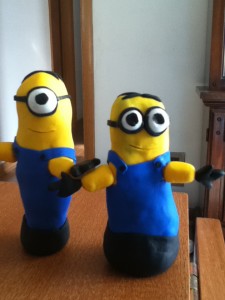 A slightly taller one-eyed yellow minion in blue coveralls and a slightly smaller two-eyed yellow minion in blue coveralls.